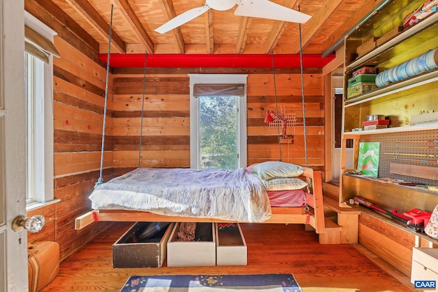 bedroom featuring wooden walls, wood-type flooring, and ceiling fan