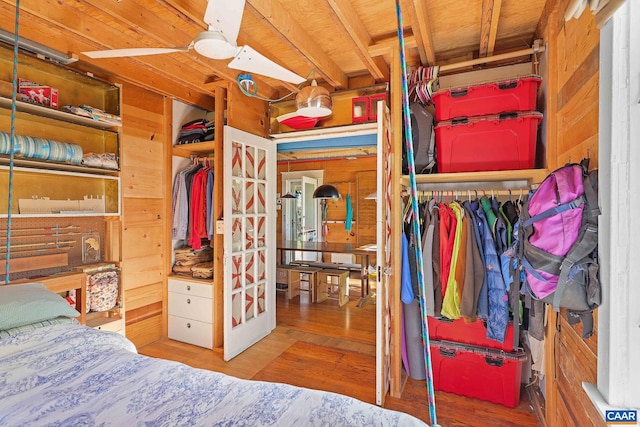 bedroom with wooden walls, a closet, light hardwood / wood-style floors, and ceiling fan