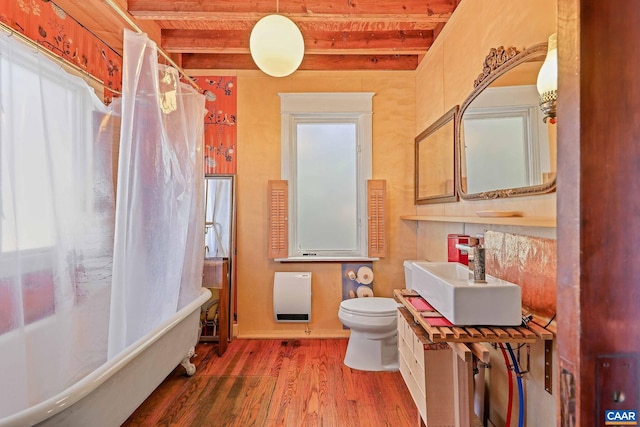 bathroom with wood-type flooring, curtained shower, toilet, heating unit, and vanity