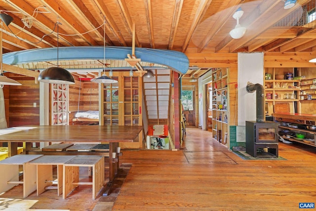 dining space with hardwood / wood-style flooring, a wood stove, and wooden walls