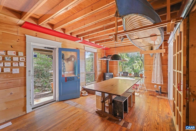 dining room featuring a wood stove, wood walls, and hardwood / wood-style flooring