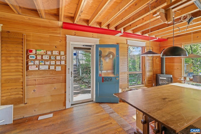 interior space featuring wood walls, a wood stove, wood-type flooring, and plenty of natural light