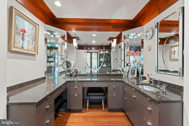 kitchen with dark stone countertops, light hardwood / wood-style flooring, kitchen peninsula, and sink