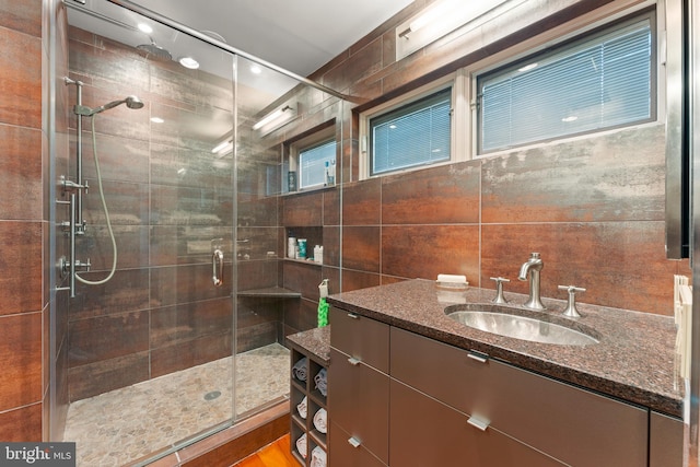 bathroom with vanity, walk in shower, and tile walls