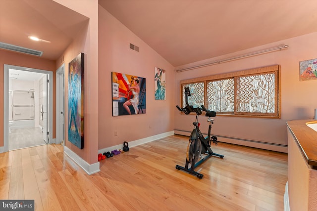 exercise room featuring a baseboard radiator, hardwood / wood-style floors, and vaulted ceiling