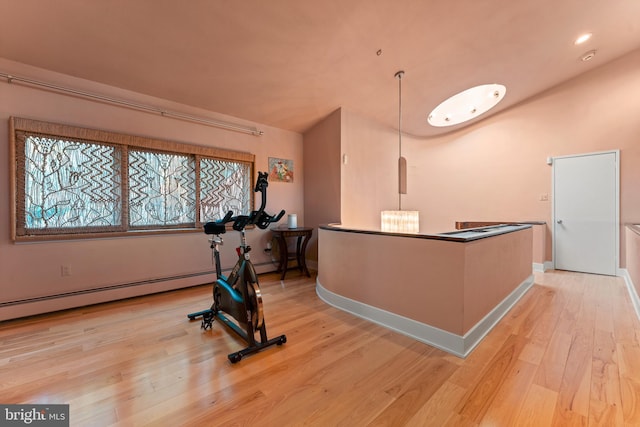 exercise area with light hardwood / wood-style flooring and a baseboard heating unit