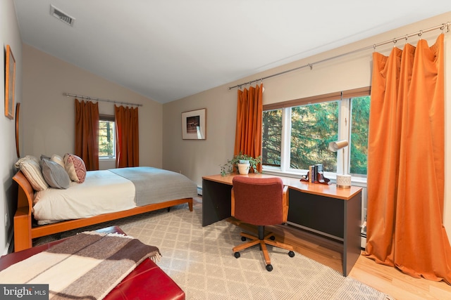 bedroom featuring a baseboard radiator, light hardwood / wood-style flooring, and vaulted ceiling