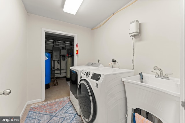 washroom with sink, electric panel, light wood-type flooring, and separate washer and dryer