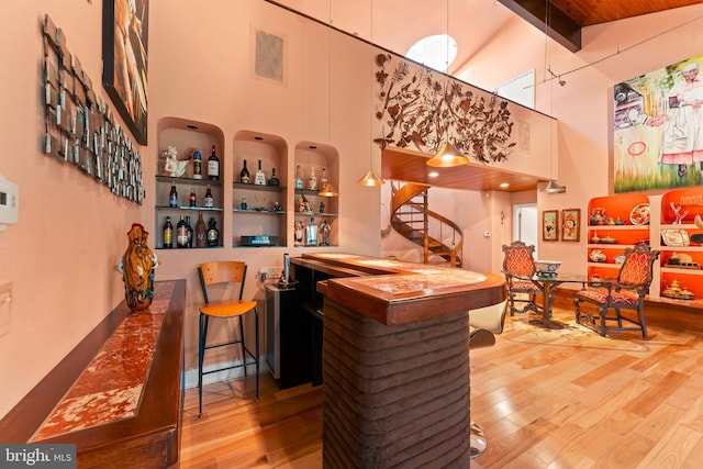 bar featuring beam ceiling, high vaulted ceiling, and hardwood / wood-style floors