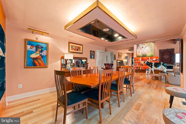 dining room featuring a textured ceiling and light wood-type flooring