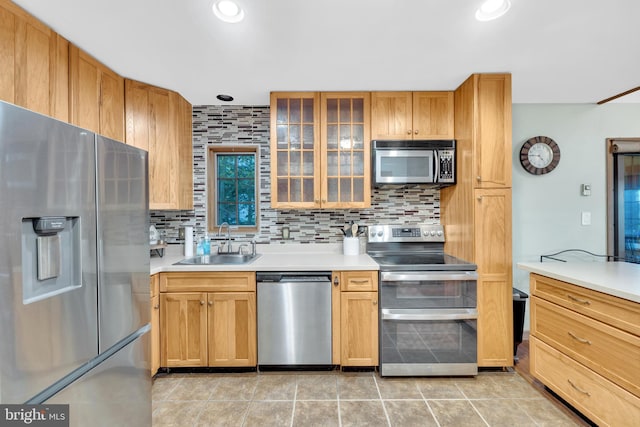 kitchen featuring a sink, tasteful backsplash, appliances with stainless steel finishes, and light countertops