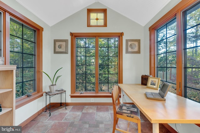 home office featuring stone tile floors, baseboards, and lofted ceiling