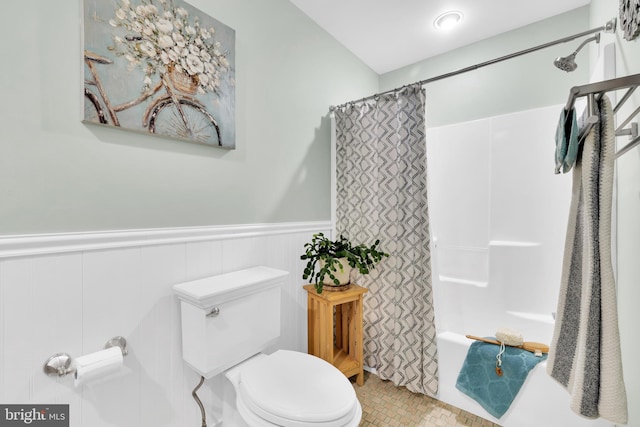 bathroom with toilet, shower / bath combo, and wainscoting