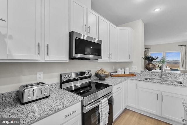 kitchen with appliances with stainless steel finishes, white cabinets, and sink