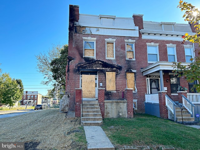 view of property with covered porch and a front yard