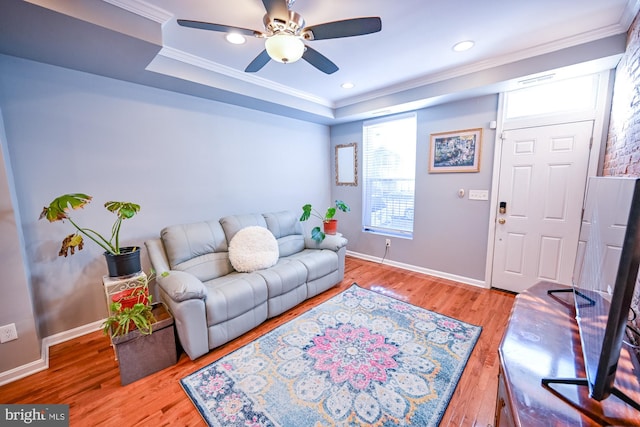 living room with hardwood / wood-style floors, ceiling fan, crown molding, and a tray ceiling