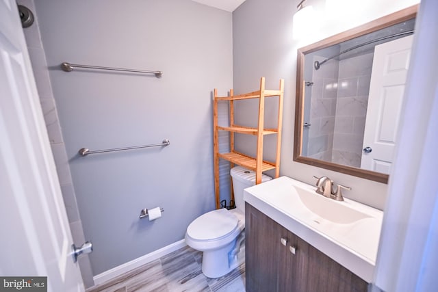 bathroom with wood-type flooring, vanity, toilet, and tiled shower