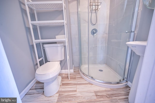 bathroom featuring walk in shower, wood-type flooring, and toilet