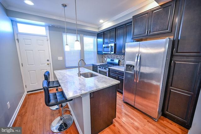 kitchen featuring stainless steel appliances, light hardwood / wood-style floors, sink, and a breakfast bar