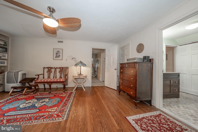 living area featuring ceiling fan, hardwood / wood-style flooring, and crown molding