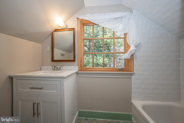 bathroom featuring vanity, tile patterned floors, a bath, and vaulted ceiling