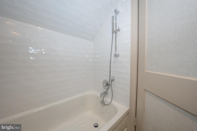 bathroom with tiled shower / bath and lofted ceiling