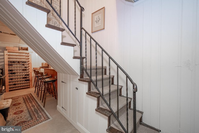 stairway featuring wooden walls and carpet