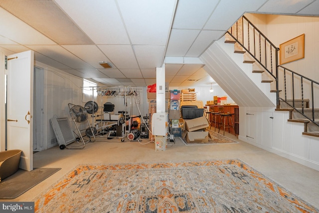 basement featuring a paneled ceiling and carpet floors