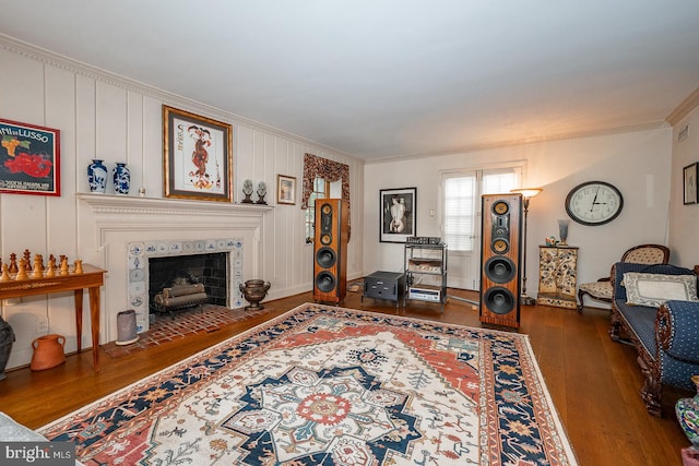 living room with crown molding, dark wood-type flooring, and a tile fireplace