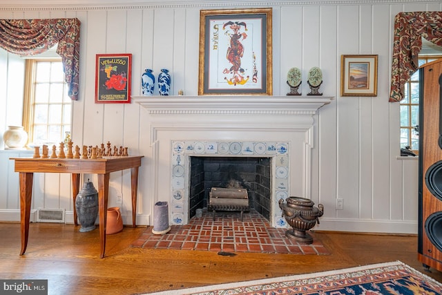 interior details featuring a tiled fireplace and wood-type flooring