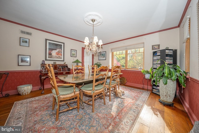 dining space featuring ornamental molding, hardwood / wood-style floors, and a notable chandelier