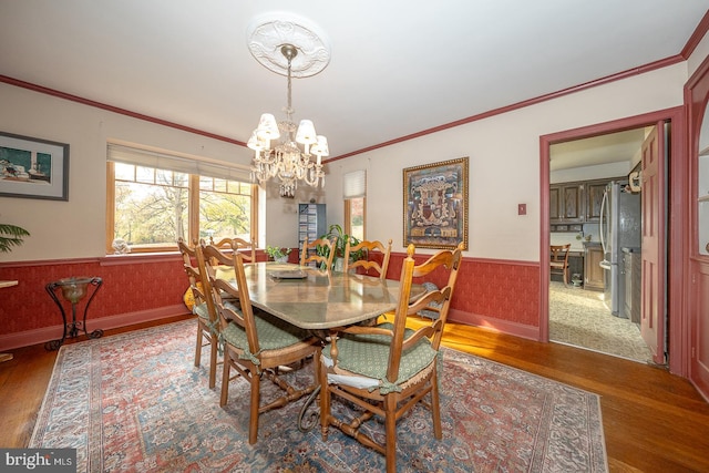 dining area with ornamental molding, a chandelier, and wood-type flooring