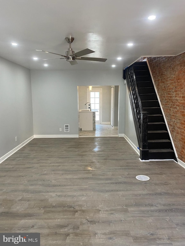 interior space with ceiling fan, brick wall, and dark hardwood / wood-style flooring