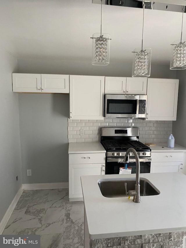 kitchen featuring appliances with stainless steel finishes, sink, hanging light fixtures, white cabinets, and decorative backsplash