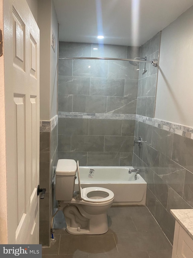 full bathroom featuring toilet, vanity, tile walls, and tile patterned flooring