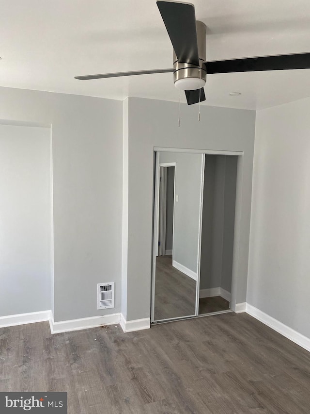 unfurnished bedroom featuring dark hardwood / wood-style floors, a closet, and ceiling fan