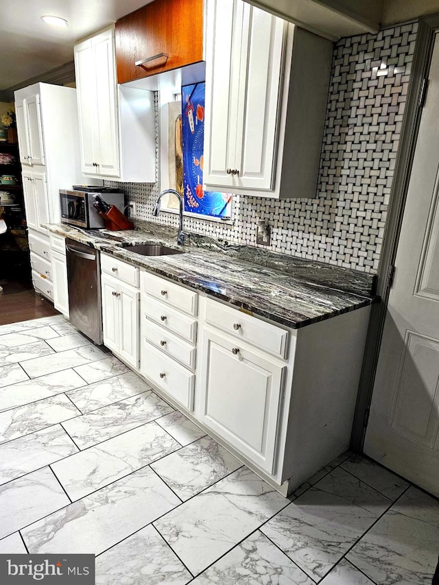 kitchen featuring tasteful backsplash, appliances with stainless steel finishes, sink, white cabinetry, and dark stone counters