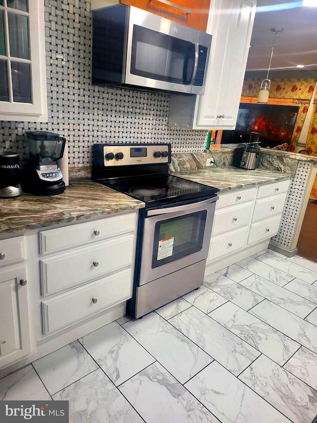 kitchen featuring tasteful backsplash, glass insert cabinets, appliances with stainless steel finishes, marble finish floor, and white cabinets