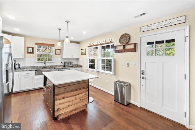 kitchen with a kitchen island, stainless steel refrigerator with ice dispenser, sink, white cabinetry, and dark hardwood / wood-style flooring