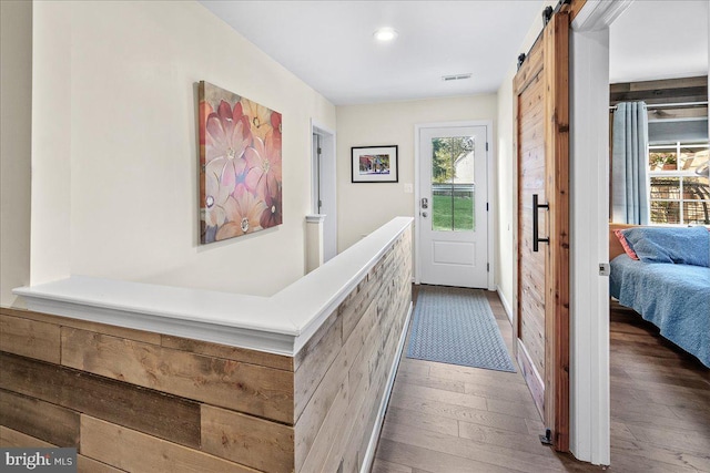 hall with dark wood-type flooring and a barn door