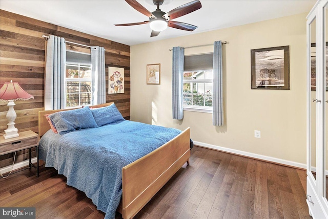 bedroom with wooden walls, multiple windows, and dark hardwood / wood-style flooring