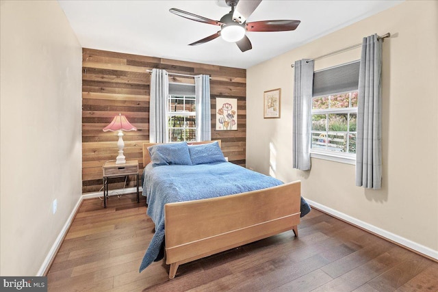 bedroom with ceiling fan, hardwood / wood-style flooring, and wood walls