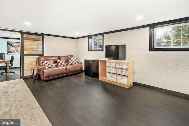 living room featuring a wealth of natural light, brick wall, and dark hardwood / wood-style floors