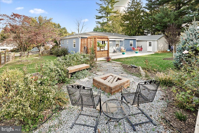 exterior space with a patio area, a fire pit, a wooden deck, and a lawn