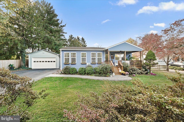 view of front of home featuring covered porch, a front yard, an outbuilding, and a garage