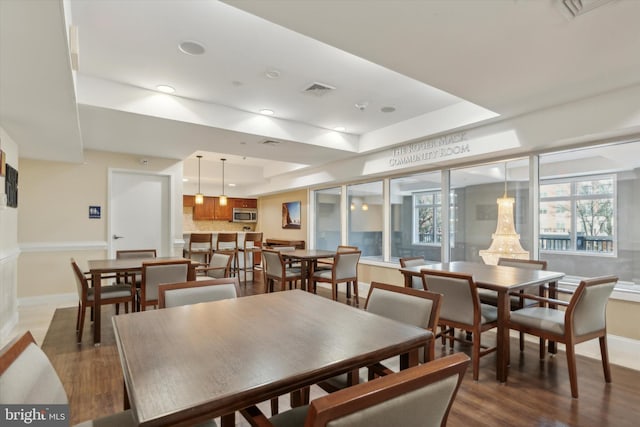 dining room featuring a raised ceiling and dark hardwood / wood-style flooring