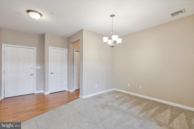 unfurnished room featuring wood-type flooring and an inviting chandelier