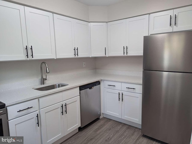 kitchen with light stone countertops, sink, dark hardwood / wood-style flooring, stainless steel appliances, and white cabinets