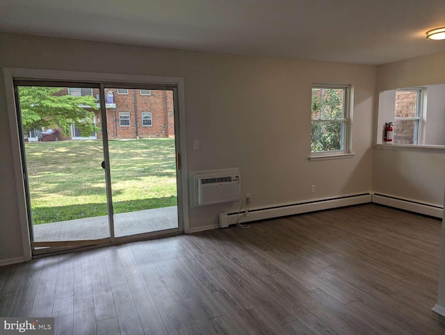 empty room featuring baseboard heating, a wall mounted AC, and hardwood / wood-style flooring