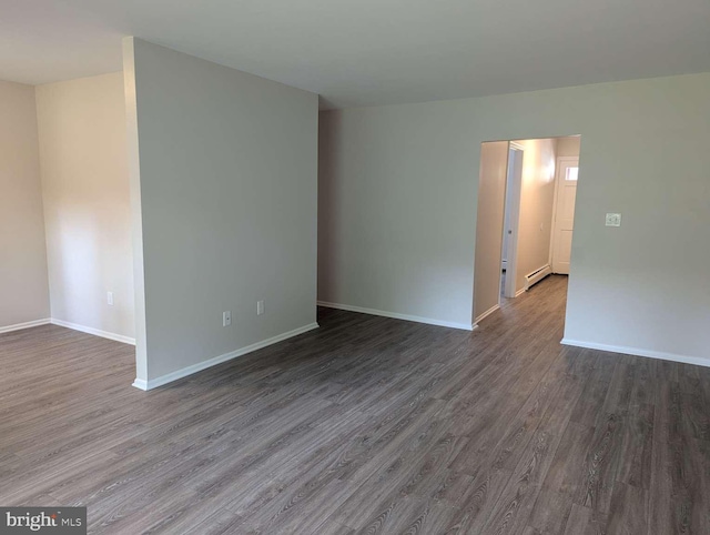 unfurnished room with a baseboard radiator and dark hardwood / wood-style flooring